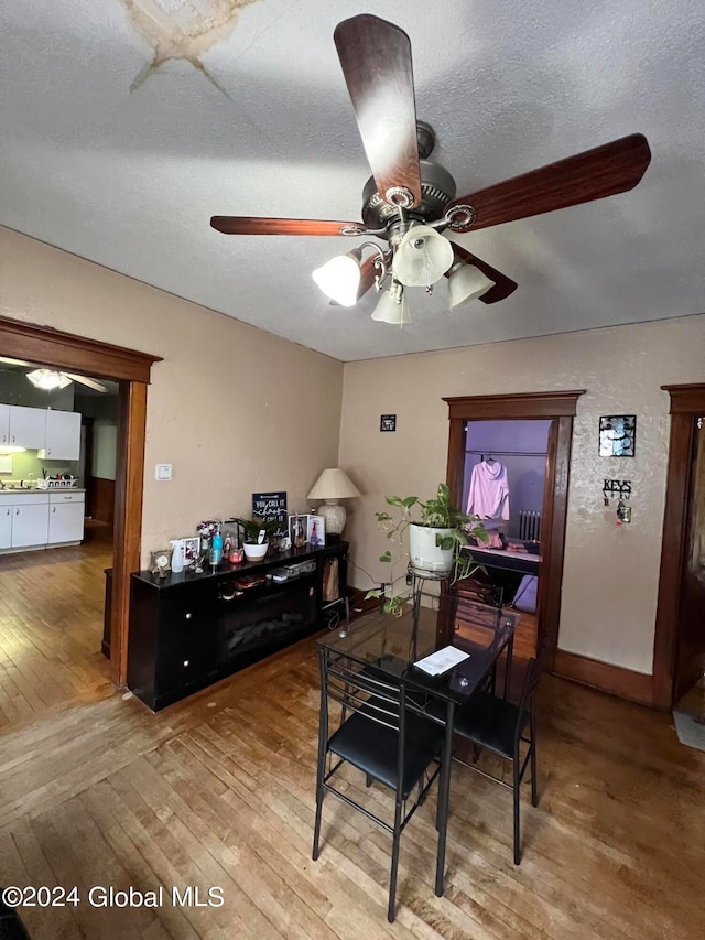 dining area with hardwood / wood-style floors, a textured ceiling, and ceiling fan