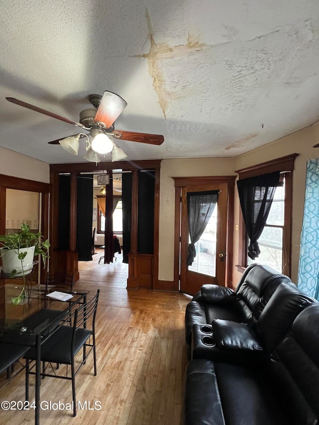 living room featuring a textured ceiling, light wood-type flooring, and ceiling fan