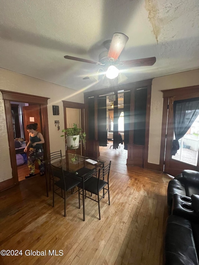 dining space with a textured ceiling, hardwood / wood-style flooring, and ceiling fan