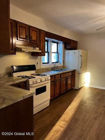 kitchen featuring white appliances, sink, ceiling fan, dark brown cabinets, and dark hardwood / wood-style flooring