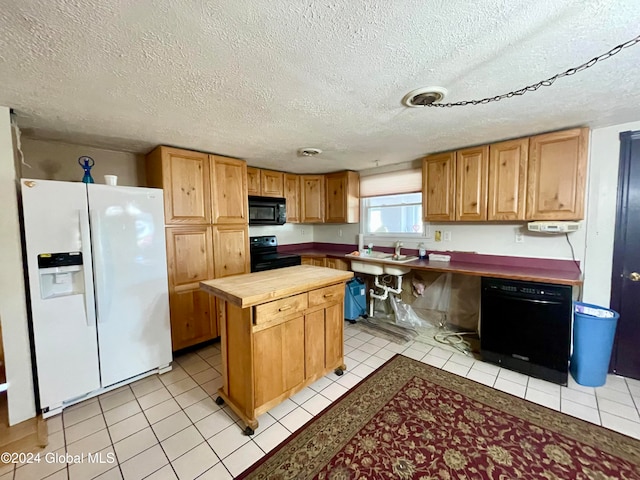 kitchen featuring a textured ceiling, light tile patterned floors, and black appliances