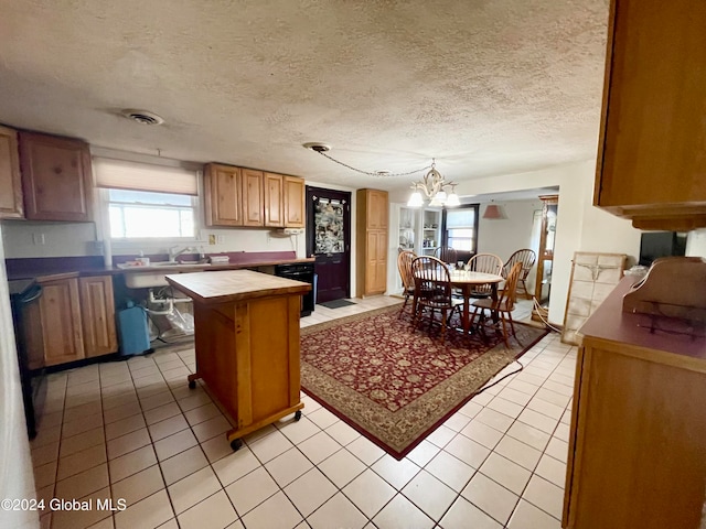 kitchen featuring hanging light fixtures, a textured ceiling, a chandelier, light tile patterned flooring, and a kitchen island