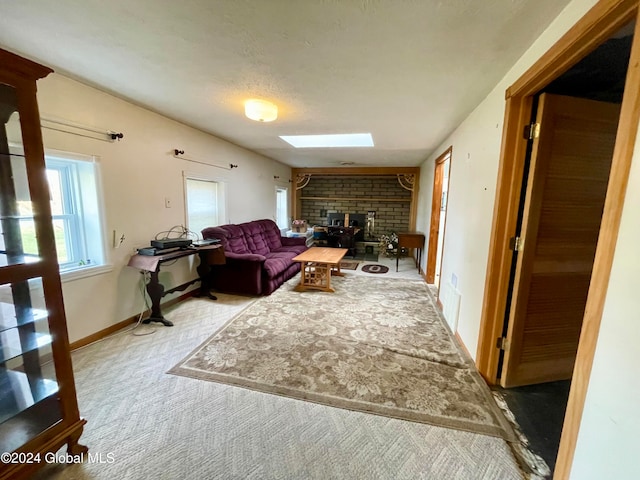 carpeted living room featuring a fireplace, a textured ceiling, and a skylight