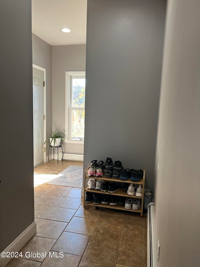 hall with a baseboard radiator and tile patterned floors