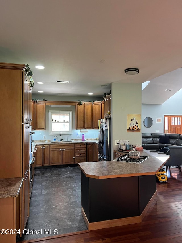 kitchen with dark hardwood / wood-style flooring, sink, stainless steel gas cooktop, and refrigerator with ice dispenser