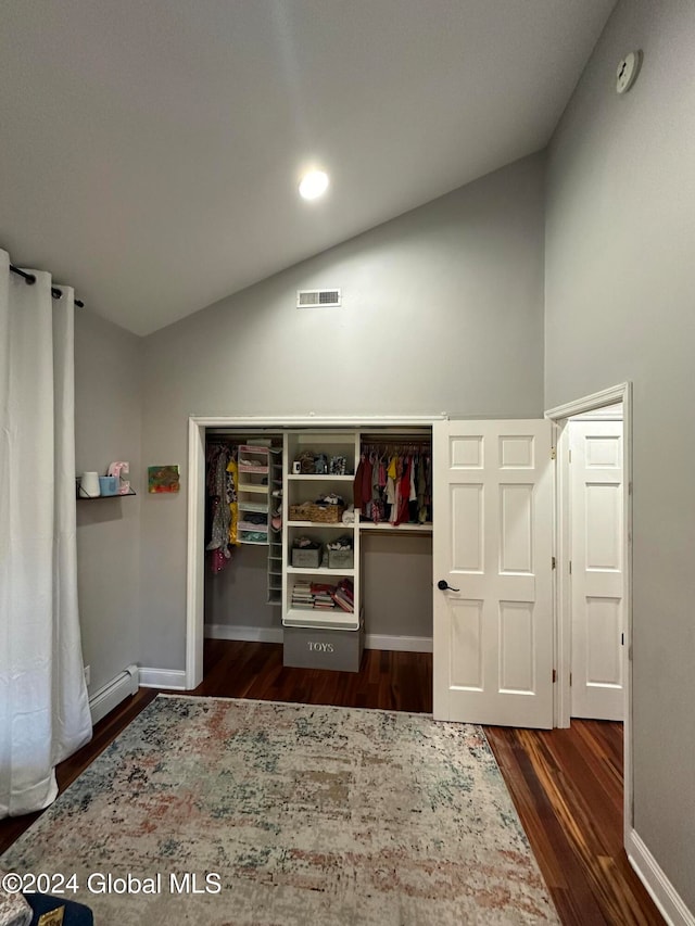 interior space with baseboard heating, lofted ceiling, dark wood-type flooring, and a closet