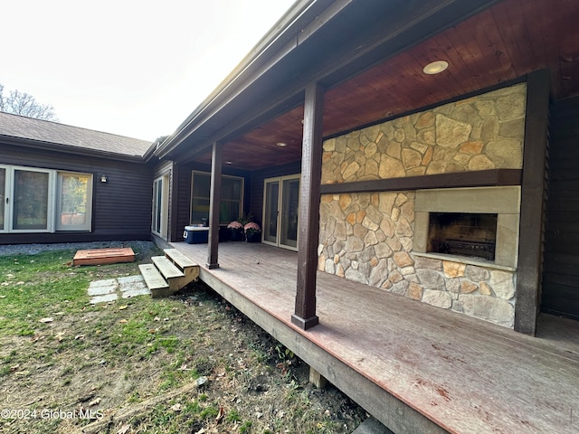 deck with a patio and an outdoor stone fireplace