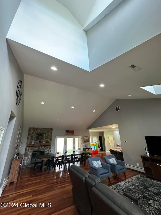 living room with a baseboard radiator, hardwood / wood-style flooring, high vaulted ceiling, and a fireplace