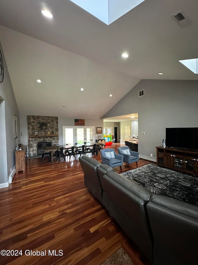 living room featuring a fireplace, dark hardwood / wood-style floors, high vaulted ceiling, and a skylight