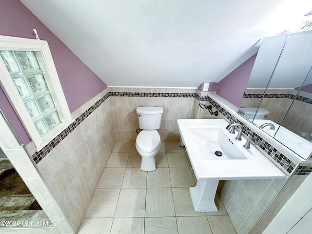 bathroom with sink, toilet, tile walls, vaulted ceiling, and tile patterned flooring