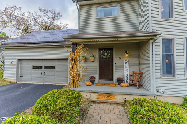 view of exterior entry featuring solar panels, a porch, and a garage