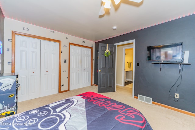 carpeted bedroom featuring ceiling fan and multiple closets