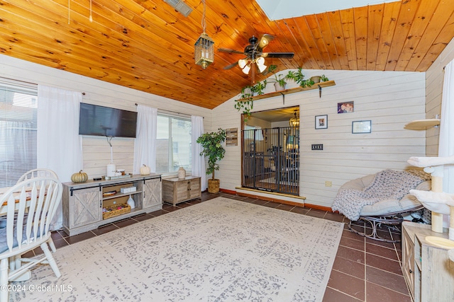 living room with wood ceiling, wood walls, vaulted ceiling with skylight, and dark tile patterned floors