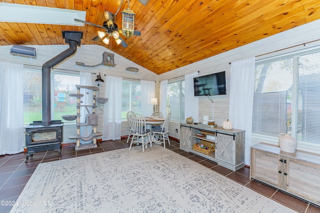 interior space featuring vaulted ceiling, wood ceiling, a wood stove, and ceiling fan