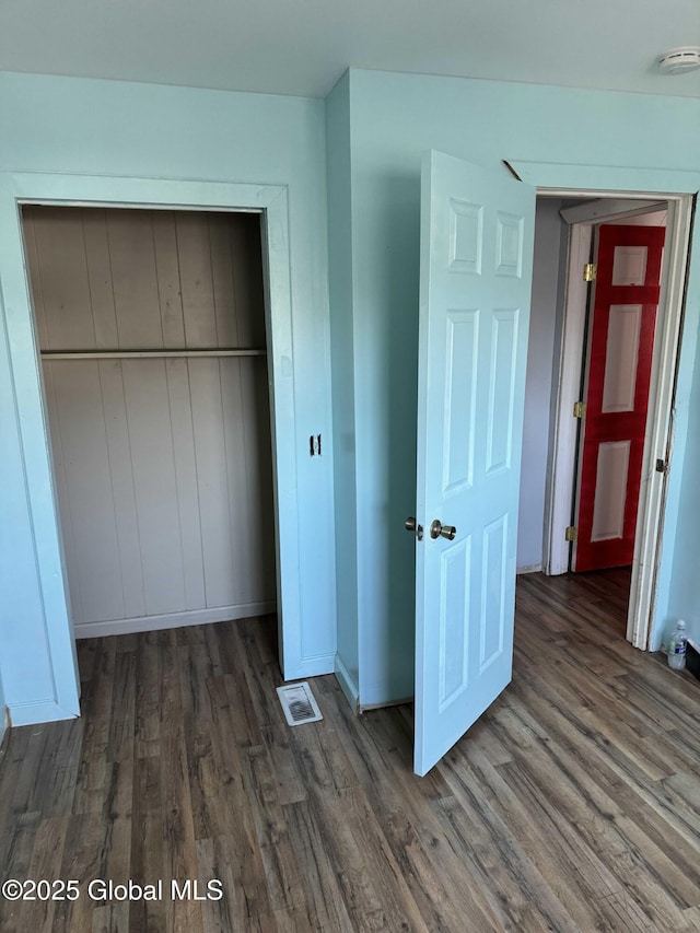 unfurnished bedroom featuring dark hardwood / wood-style floors and a closet