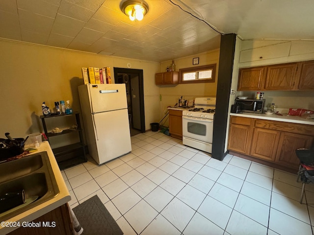 kitchen featuring white appliances, sink, lofted ceiling, ornamental molding, and light tile patterned floors