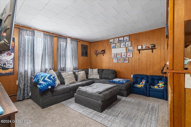 carpeted living room featuring wooden walls