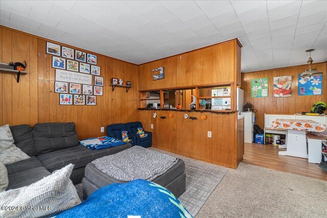 carpeted living room featuring wooden walls