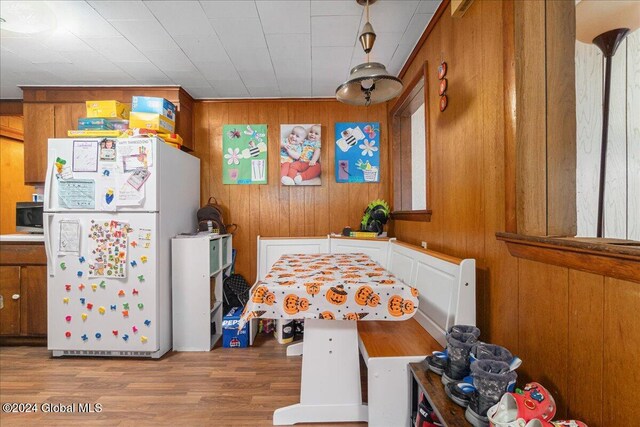 kitchen featuring light hardwood / wood-style flooring, wood walls, and white fridge