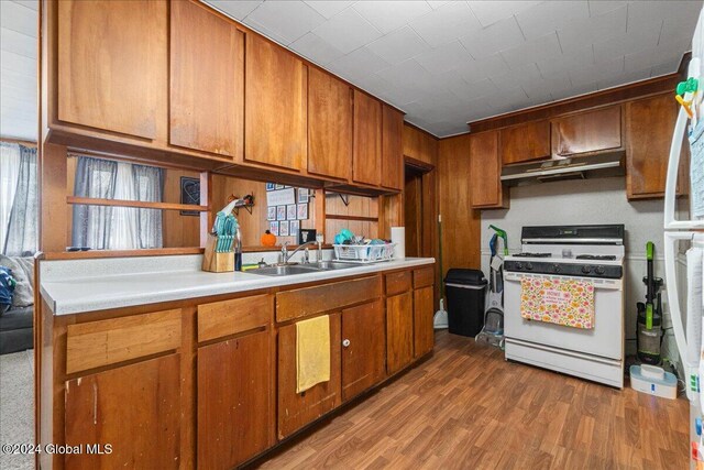 kitchen with white gas range, sink, and light hardwood / wood-style flooring