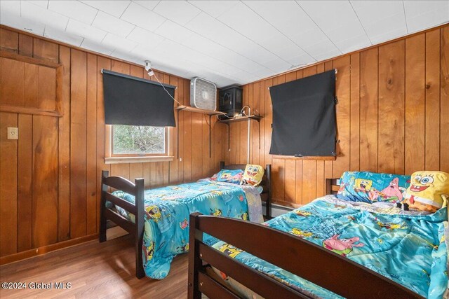 bedroom with wooden walls and wood-type flooring