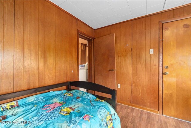 bedroom with wood walls and light hardwood / wood-style flooring