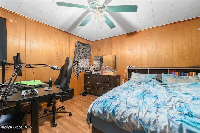 bedroom featuring wood walls, light hardwood / wood-style floors, and ceiling fan