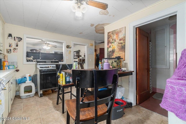 interior space featuring ceiling fan, white cabinetry, range, and ornamental molding