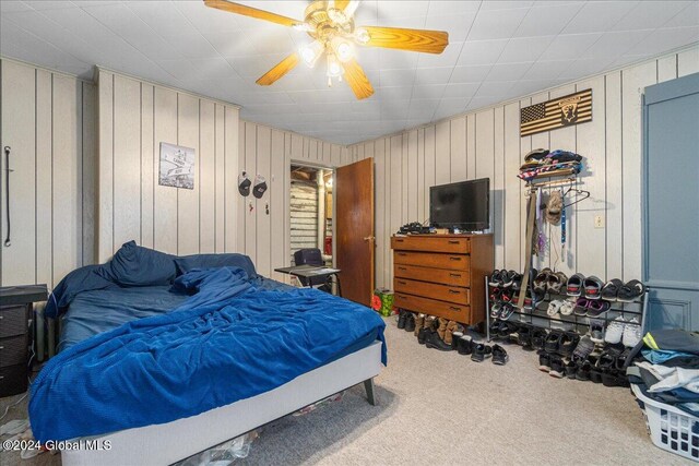 bedroom with wood walls, ceiling fan, and carpet floors