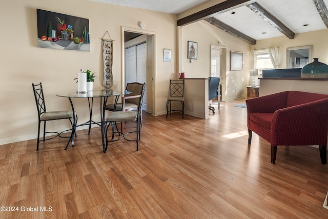 dining room with lofted ceiling with beams and light wood-type flooring