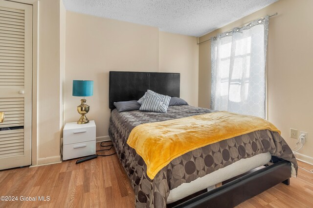 bedroom with light hardwood / wood-style flooring and a textured ceiling