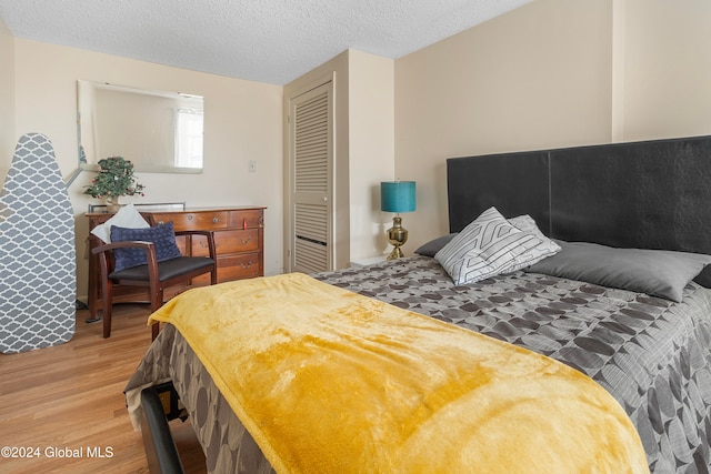 bedroom with a textured ceiling, hardwood / wood-style flooring, and a closet