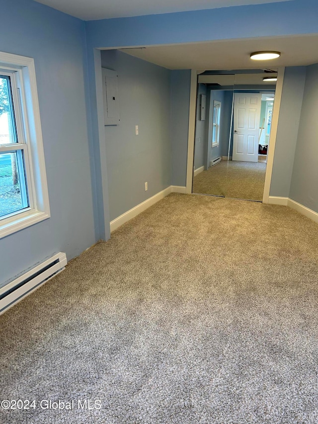 carpeted empty room featuring electric panel and a baseboard radiator