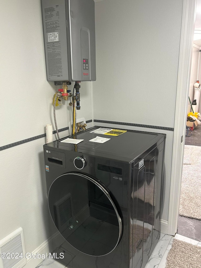 clothes washing area featuring water heater and washer / dryer