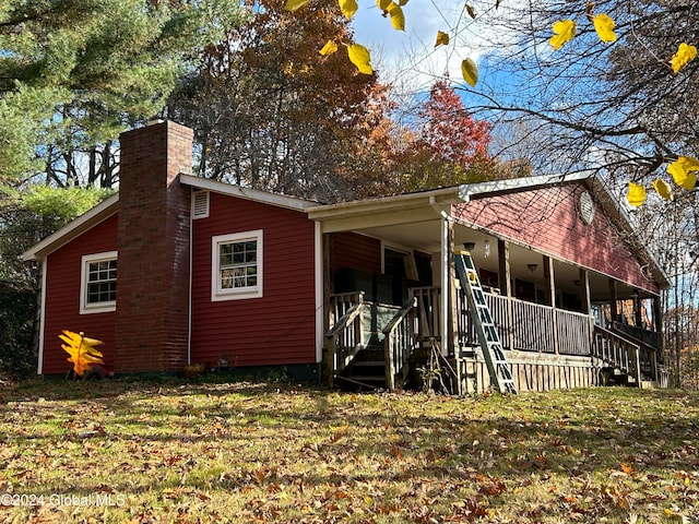 view of property exterior with covered porch and a lawn