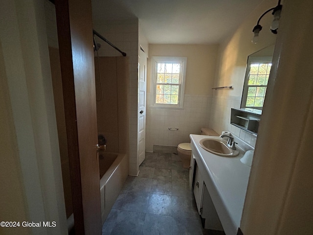 full bathroom featuring toilet, vanity,  shower combination, and tile walls