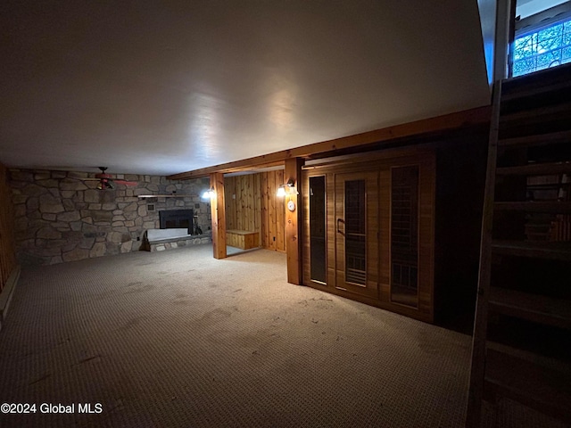 basement with a fireplace, carpet flooring, and wood walls