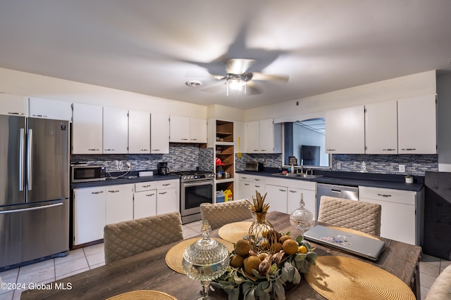 kitchen with backsplash, sink, light tile patterned floors, white cabinetry, and stainless steel appliances