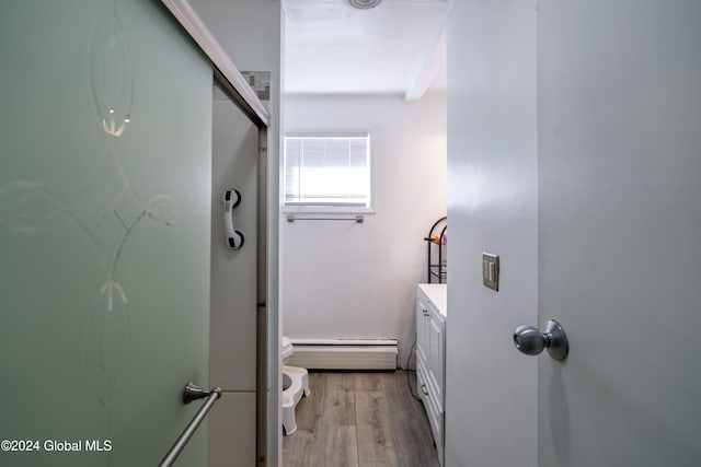 bathroom featuring baseboard heating, hardwood / wood-style floors, vanity, and toilet