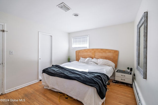 bedroom featuring light wood-type flooring and baseboard heating