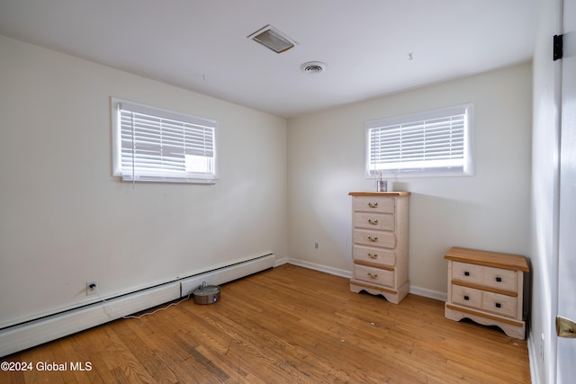 unfurnished bedroom with light hardwood / wood-style flooring and a baseboard heating unit