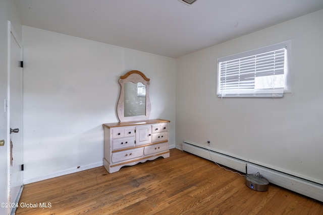 bedroom with wood-type flooring and a baseboard heating unit