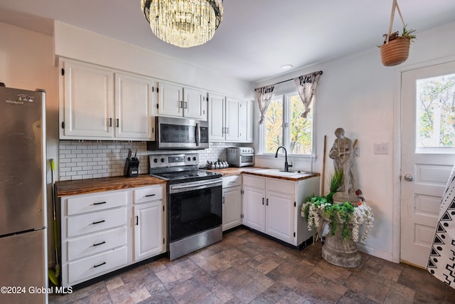 kitchen featuring backsplash, an inviting chandelier, sink, white cabinetry, and stainless steel appliances