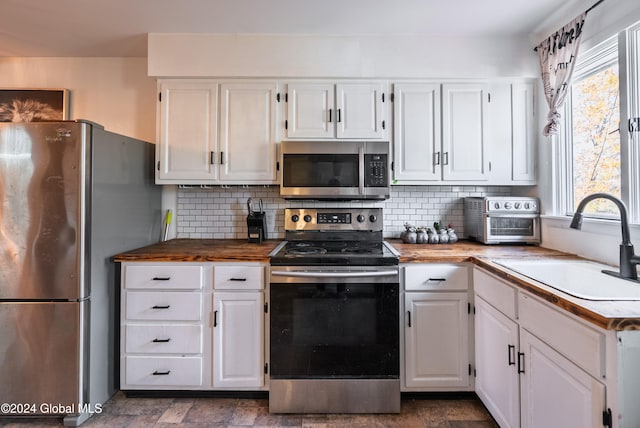 kitchen featuring white cabinets, appliances with stainless steel finishes, tasteful backsplash, and sink