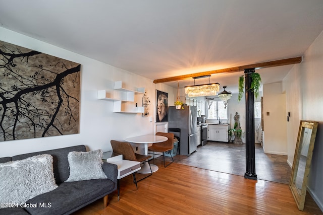 living room with a chandelier, hardwood / wood-style floors, beam ceiling, and sink