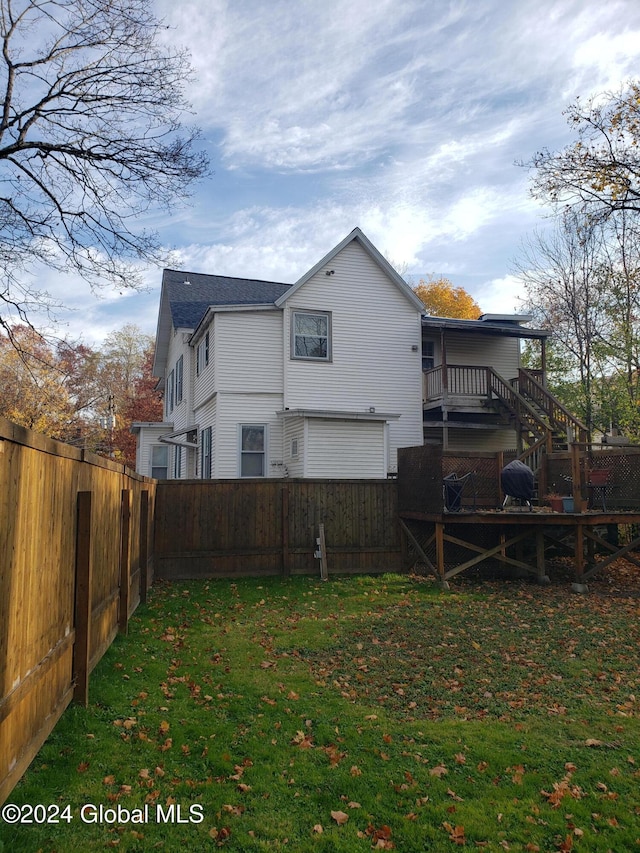 back of property featuring a wooden deck and a yard