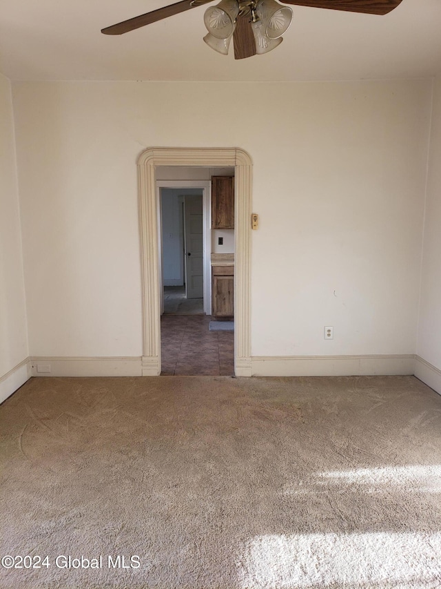 unfurnished room with ceiling fan and dark colored carpet