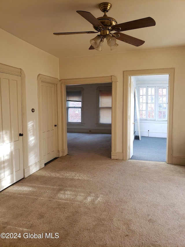 empty room with carpet flooring, plenty of natural light, and ceiling fan