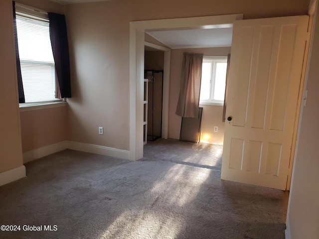 empty room with vaulted ceiling and light colored carpet