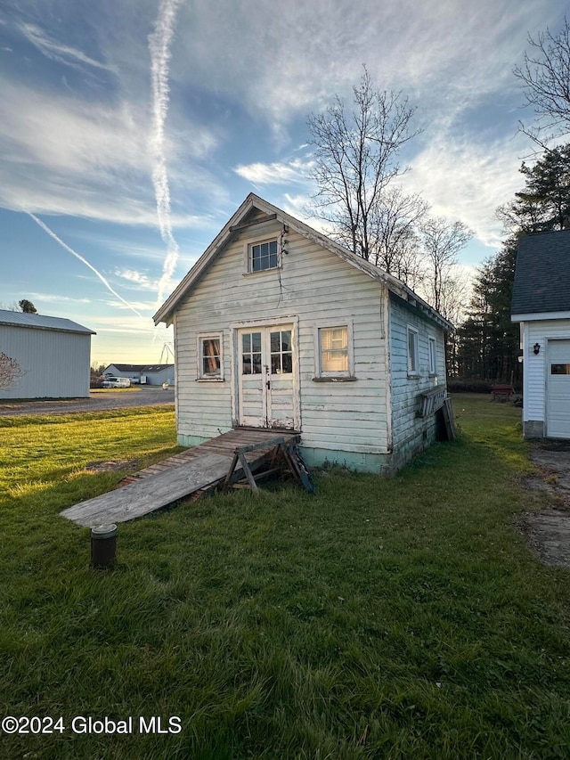 back of house featuring an outbuilding and a lawn